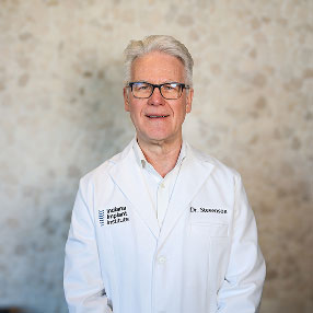 Dr. Howard Stevenson, Oral & Maxillofacial Surgeon at Indiana Implant Institute, smiling in a white lab coat