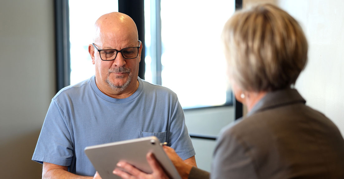 Indiana Implant Institute staff member reviewing dental implant treatment details with a patient on a tablet