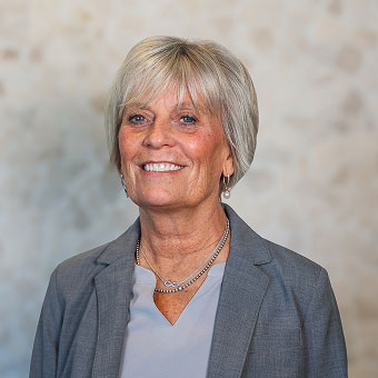 Ginny Reinhertz, Prosthodontic Team Lead at Indiana Implant Institute, smiling in a grey blazer