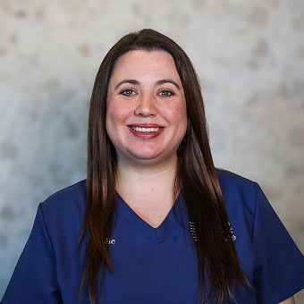 Leslie Pastuszak, Surgery Team member at Indiana Implant Institute, smiling in blue scrubs