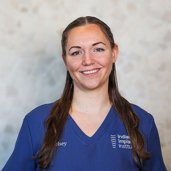 Kelsey Cardin, Surgery Team member at Indiana Implant Institute, smiling in blue scrubs